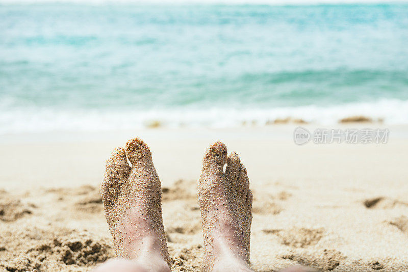 Pedn Vounder Cornwall海滩上，男人被沙子覆盖的脚